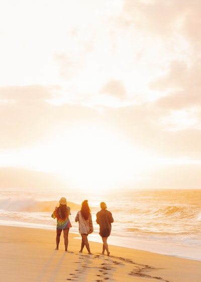 Standing on the beach three men and women of the sunset
